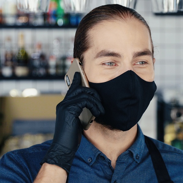 Adult restaurant worker wearing mask taking phone order